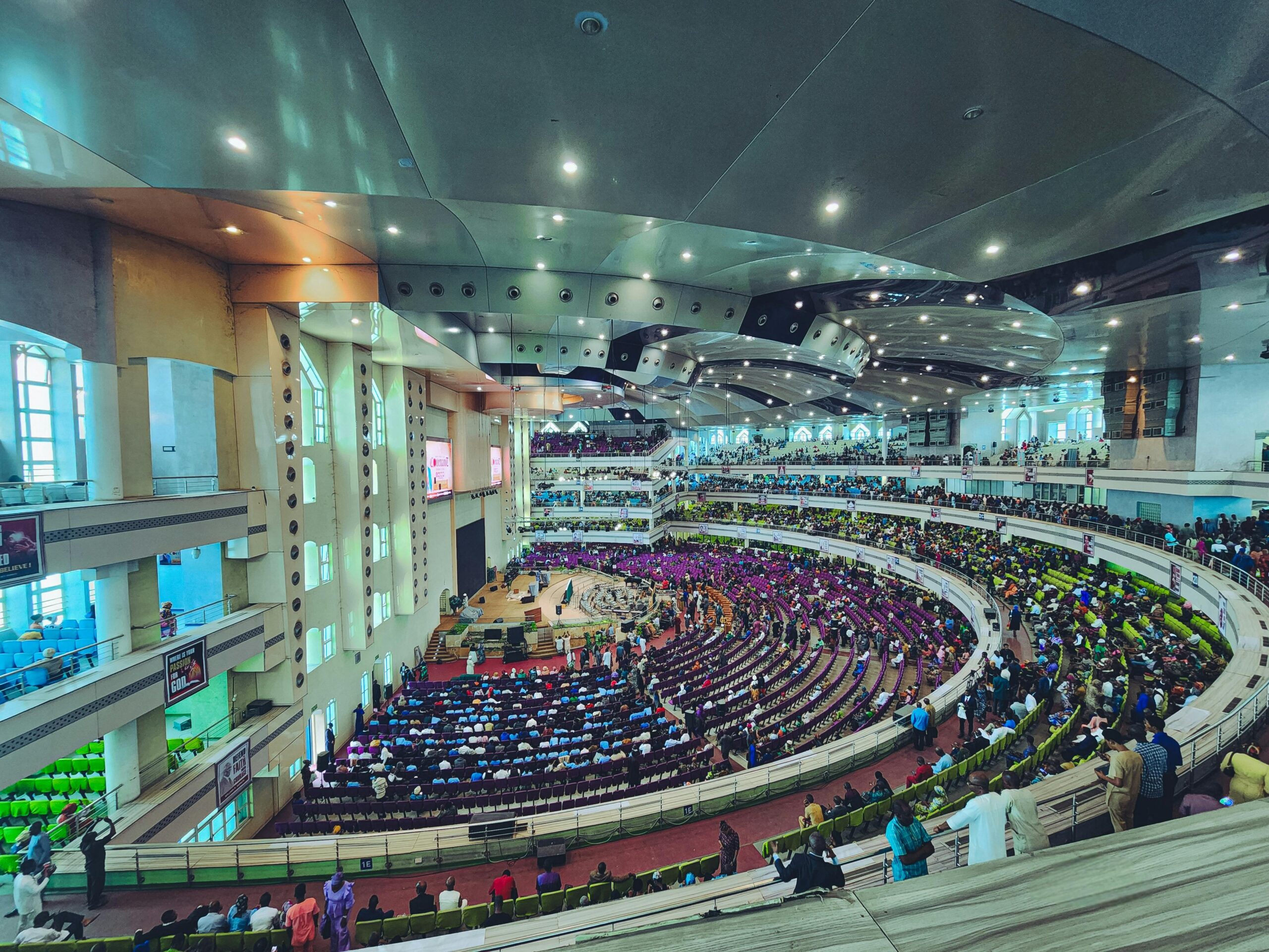 Panoramic view of a spacious indoor auditorium filled with a diverse crowd attending an event.