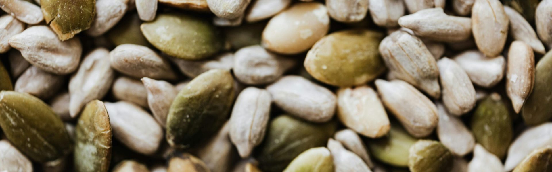 A close-up view of mixed raw pumpkin and sunflower seeds, showcasing their textures and natural colors.
